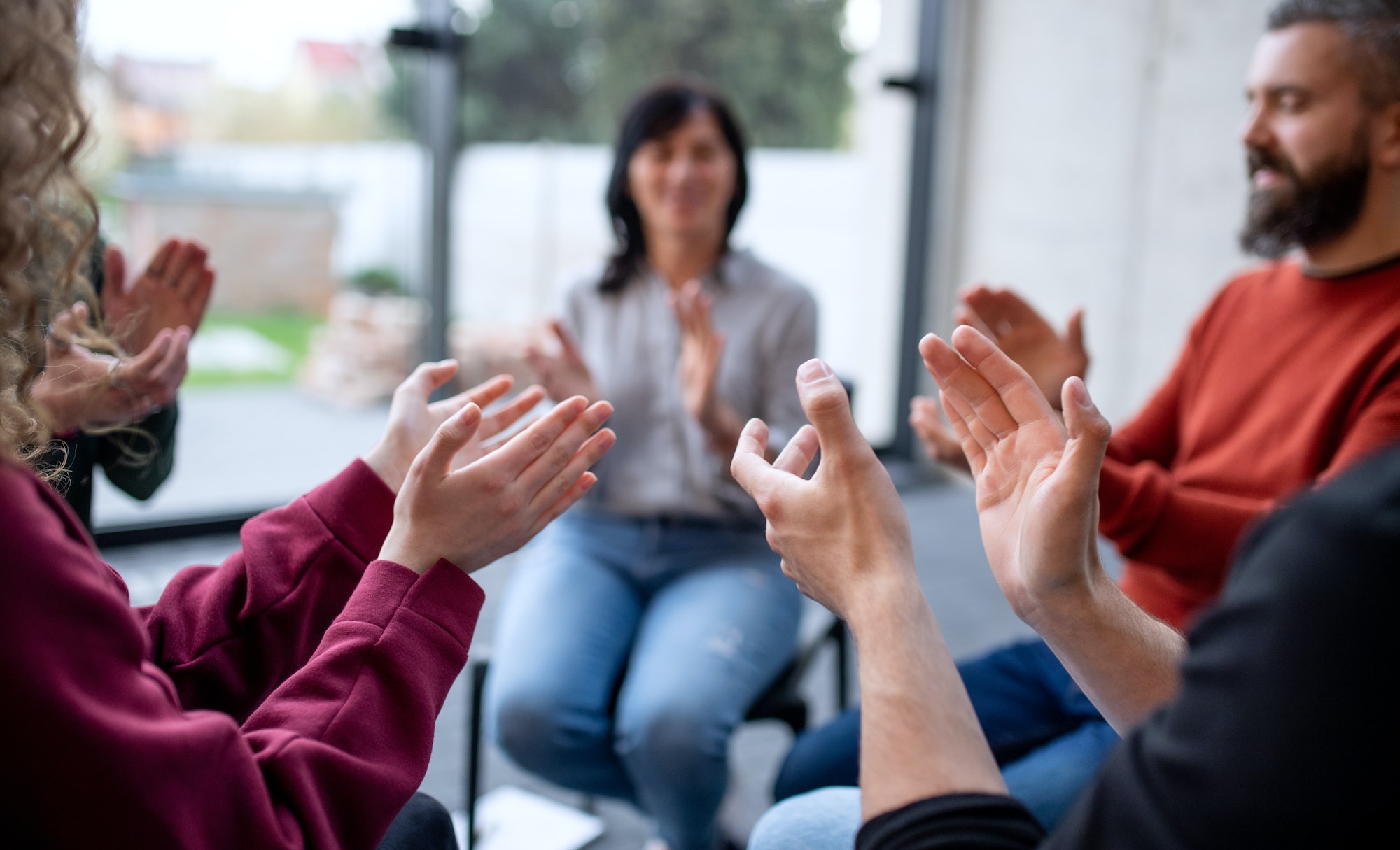 Men and women sitting in circle during group therapy, clapping