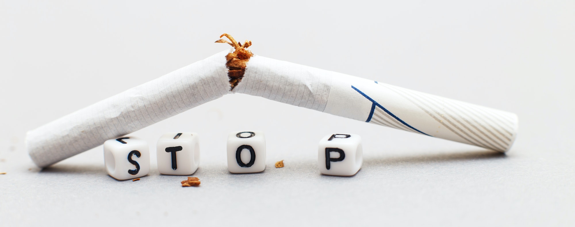 broken cigarette with the word stop on a gray background close. stop smoking concept.banner