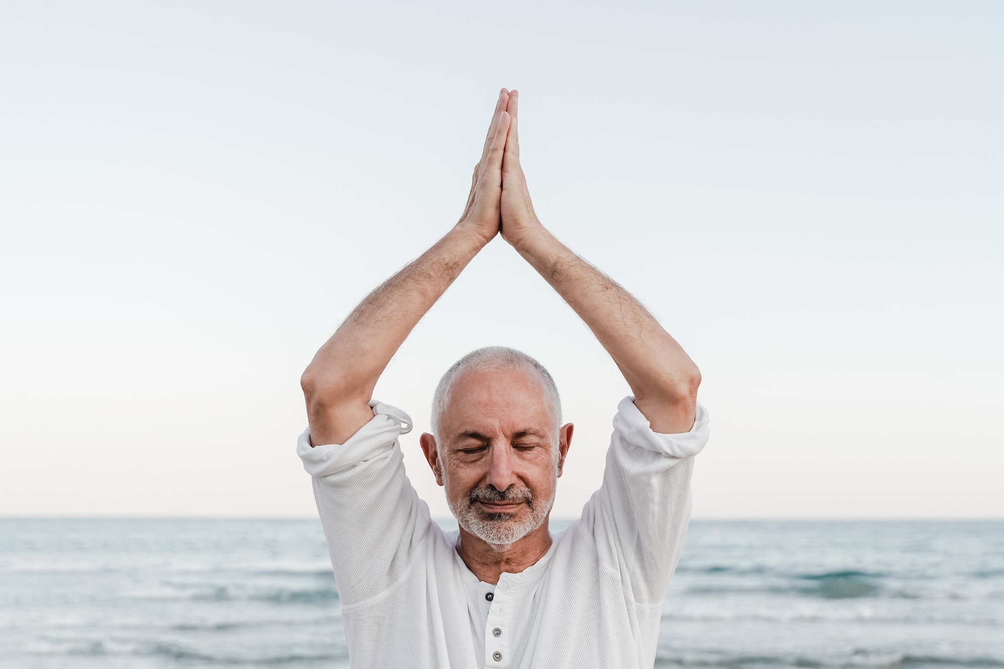 Hypnose Raucherentwöhnung: Senior man doing yoga meditation outdoor at the beach - Elderly and healthy lifestyle