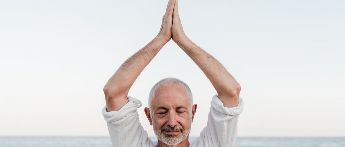 Hypnose Raucherentwöhnung: Senior man doing yoga meditation outdoor at the beach - Elderly and healthy lifestyle