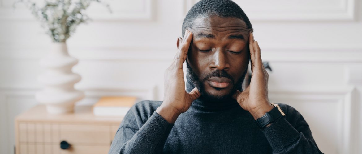 Stressed young african man employee with frustrated face expression suffering from headache